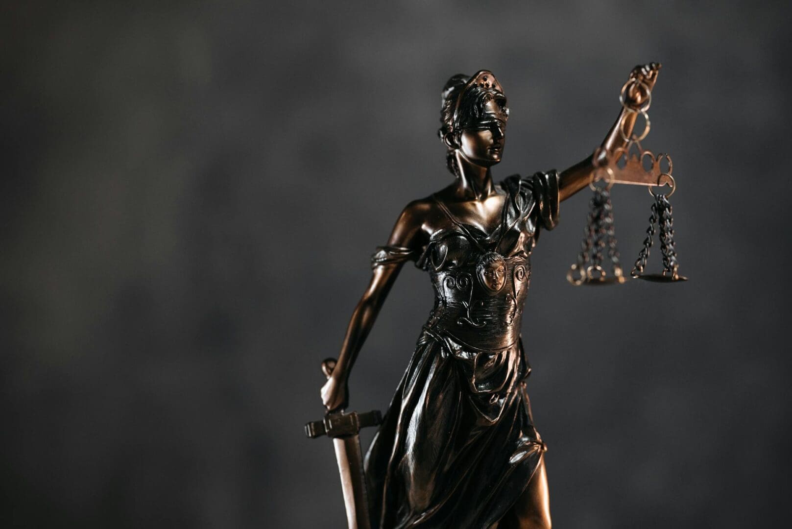 Blindfolded Lady Justice statue holding scales.
