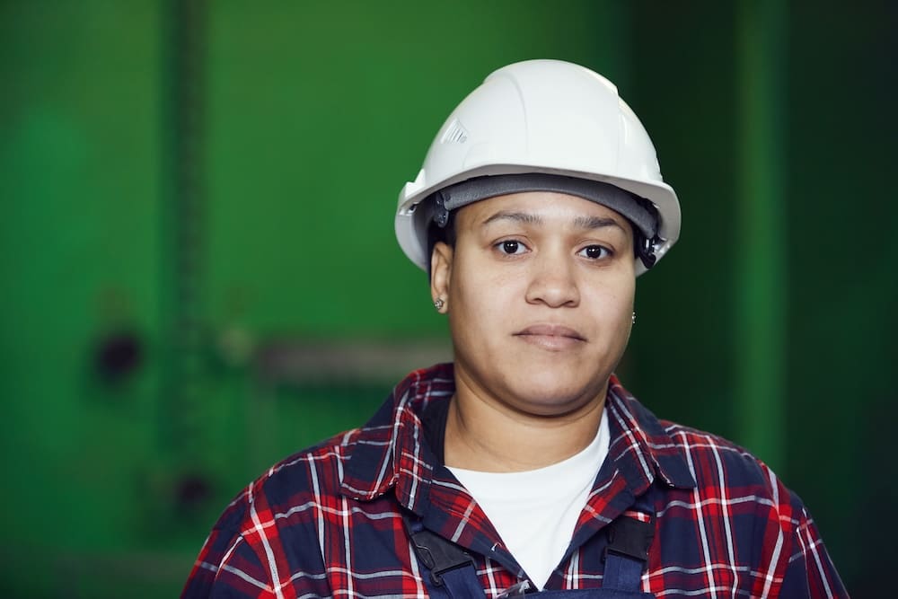 Person wearing hard hat and plaid shirt.