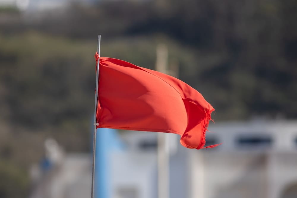 Red flag fluttering on pole, blurred background