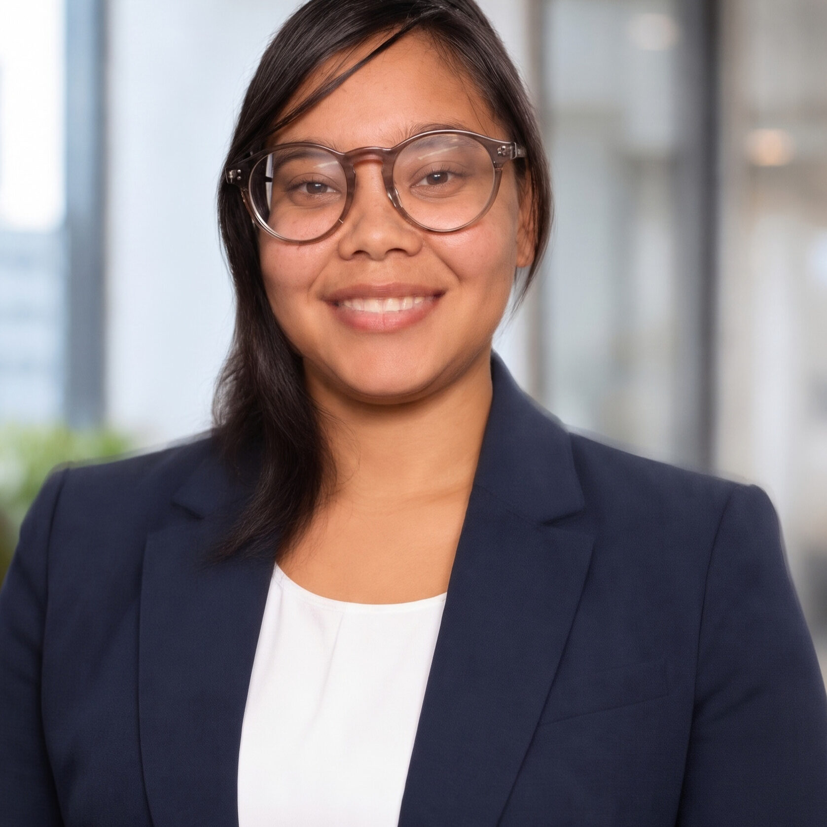 A photo of a woman wearing glasses, a white shirt, and navy blazer.