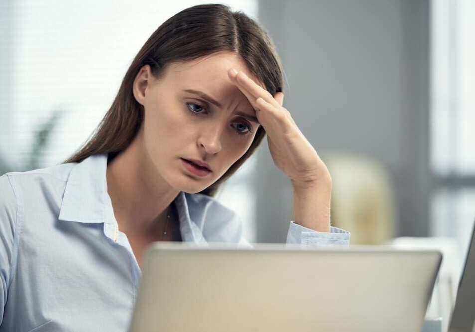 Woman looking stressed while using laptop.