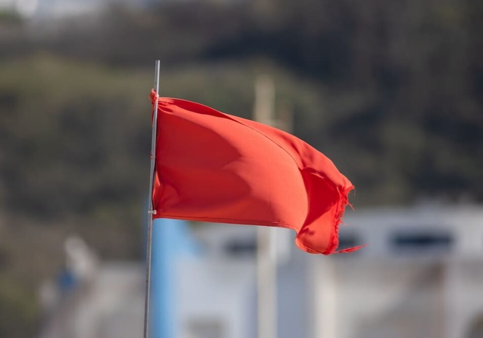 Red flag fluttering on pole, blurred background