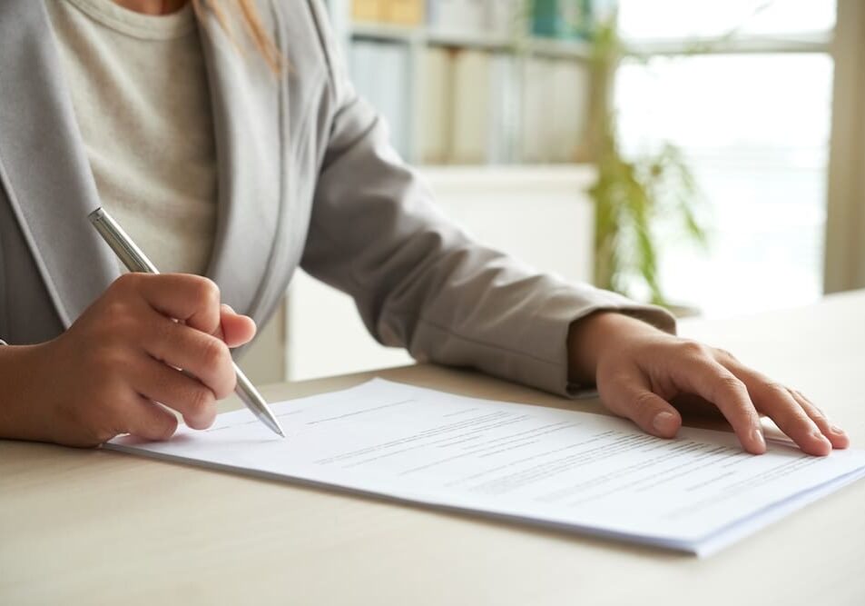 Person signing a document at desk.