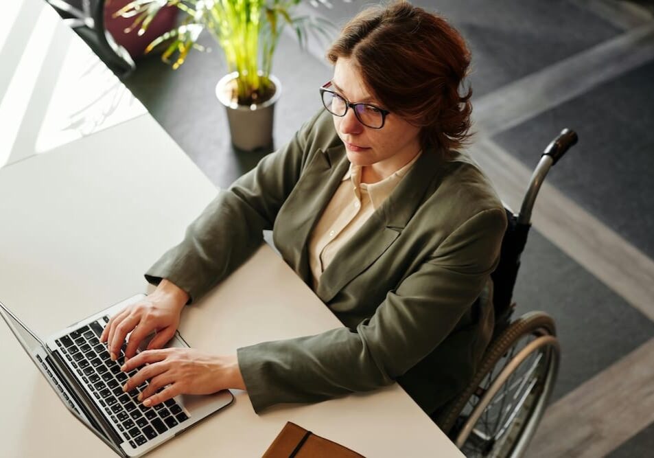Person in wheelchair working on a laptop.