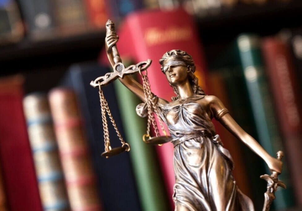 Lady Justice statue with scales, books background.