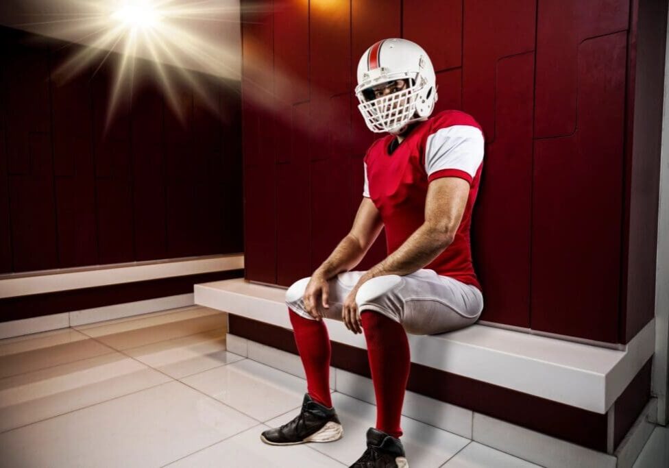 Football player sitting in locker room.